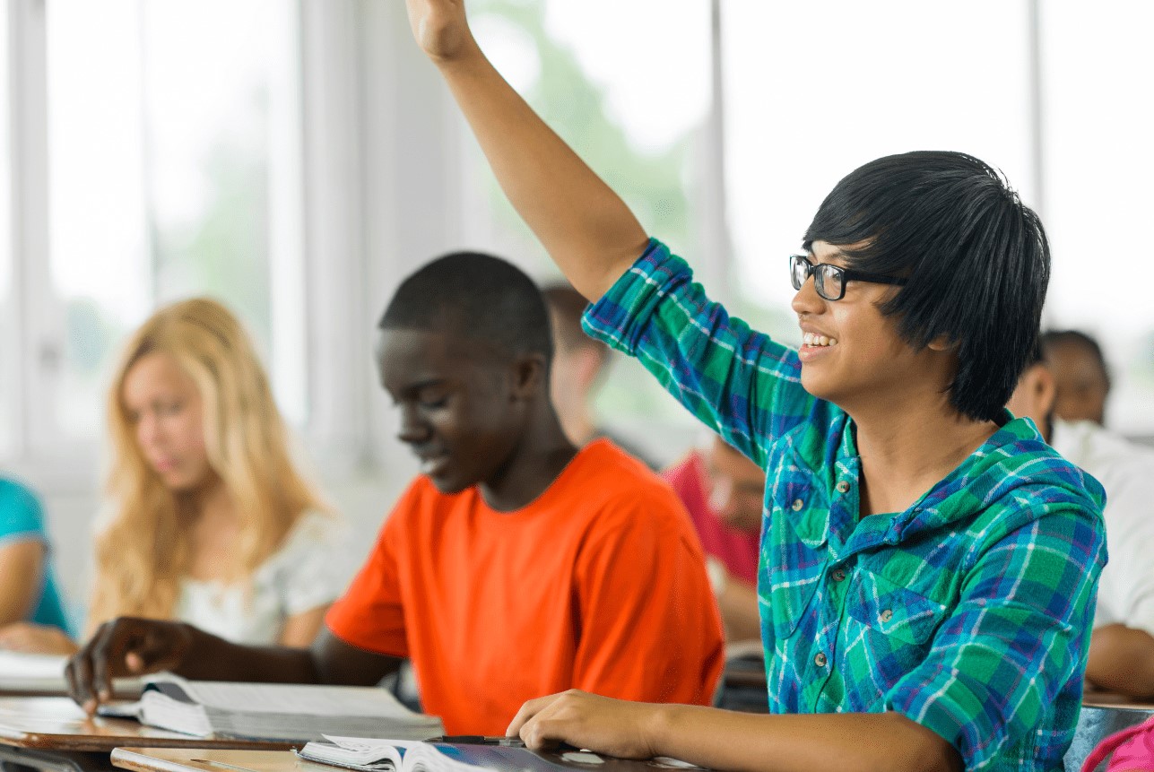 Student smiling and raising his hand