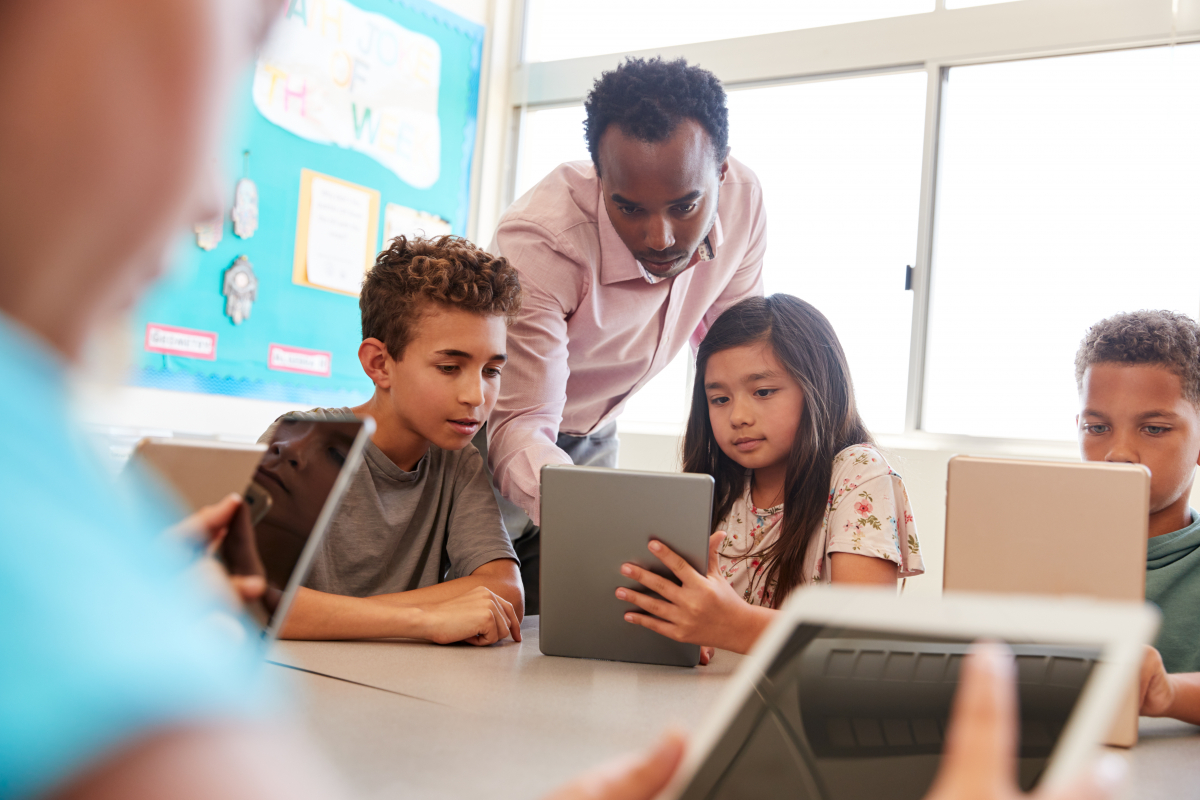 Teacher showing student how to use tech in classroom